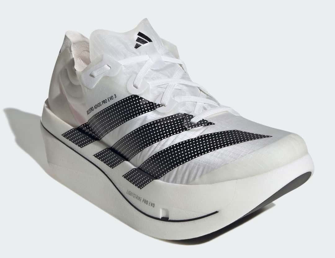 adidas Adizero Adios Pro Evo 3 en diagonal sobre fondo gris claro, con la mediasuela blanca alta, la línea negra que la recorre, las tres tiras negras en el costado y el cuello blanco con el logo de adidas