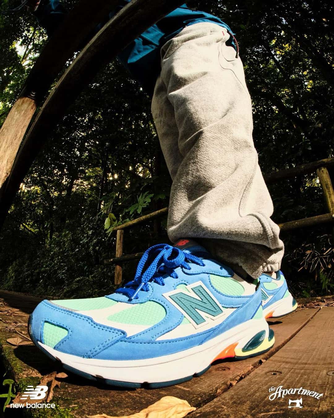 Primer plano de la New Balance 2010 GORE-TEX Kingfisher en el pie, con la gamuza azul y la N verde, sobre un puente de madera