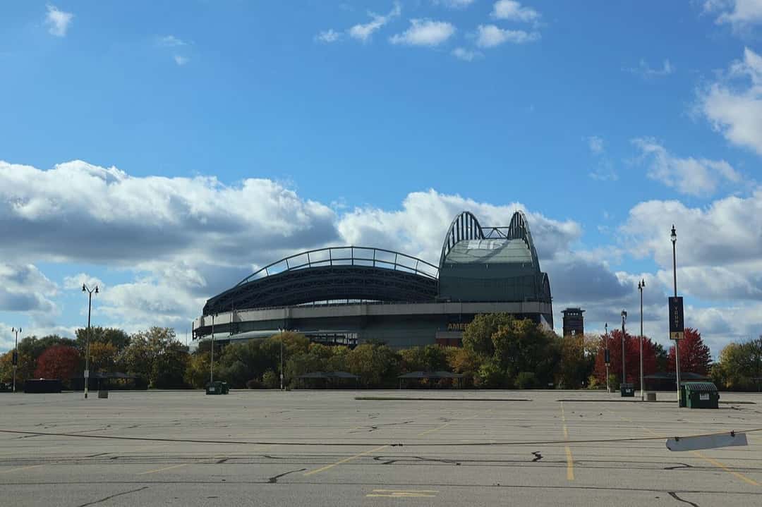 Imagen del estadio: el American Family Field visto desde el estacionamiento, con el techo cerrado y árboles rojos y amarillos alrededor