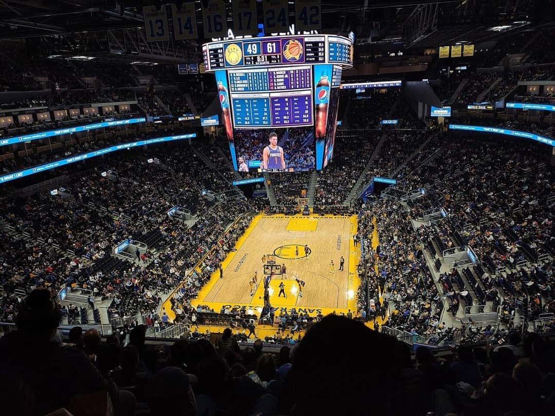 El Chase Center de San Francisco visto desde lo alto de las tribunas durante un partido de los Golden State Warriors, con la cancha y la pantalla gigante en el centro