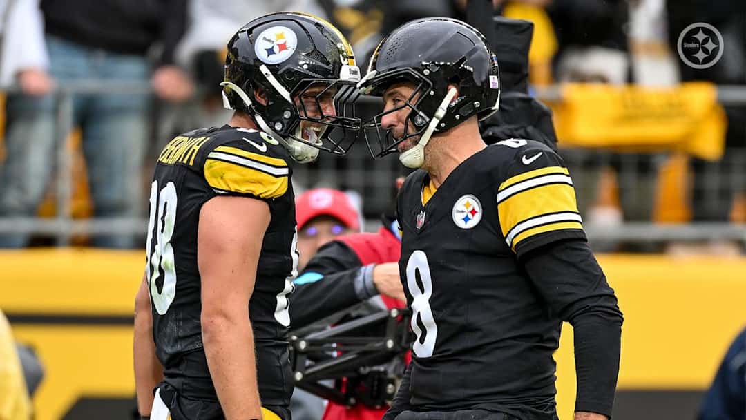 Pat Freiermuth, con el número 88, y Aaron Rodgers, con el 8, se miran cara a cara para festejar un touchdown de los Steelers en el Acrisure Stadium