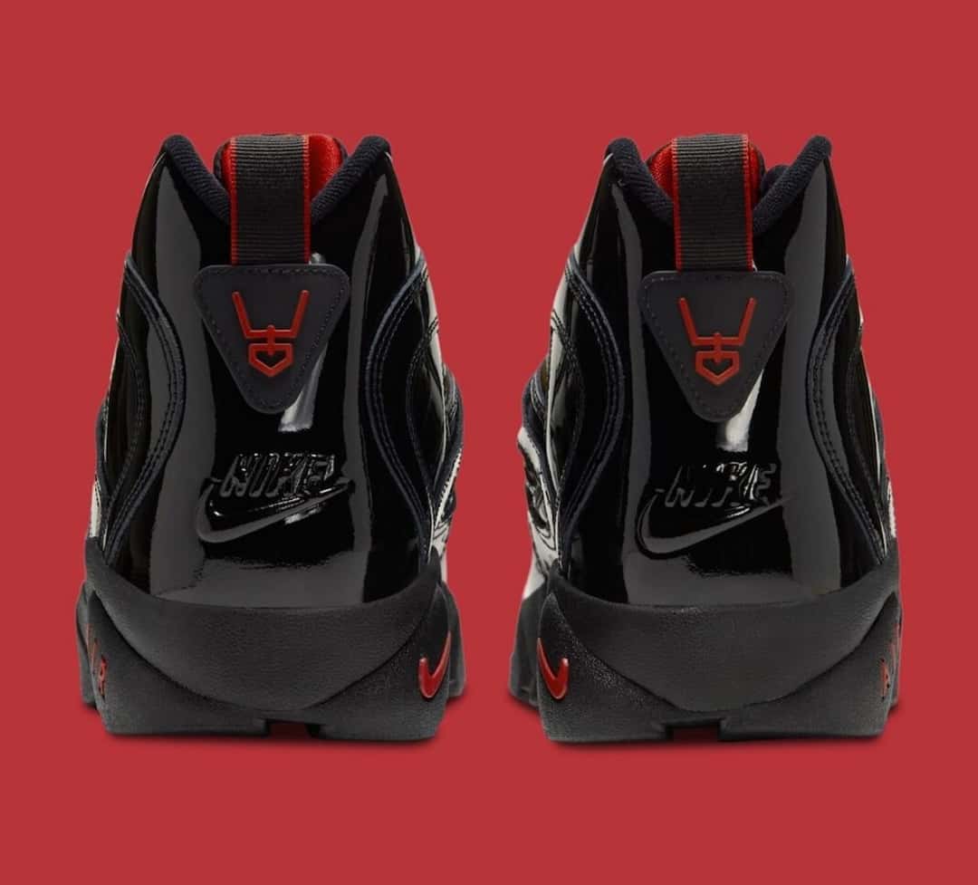 Talones de la Nike Air Diamond Turf 2 en charol negro, con el logo de Deion Sanders en rojo y la palabra Nike en relieve