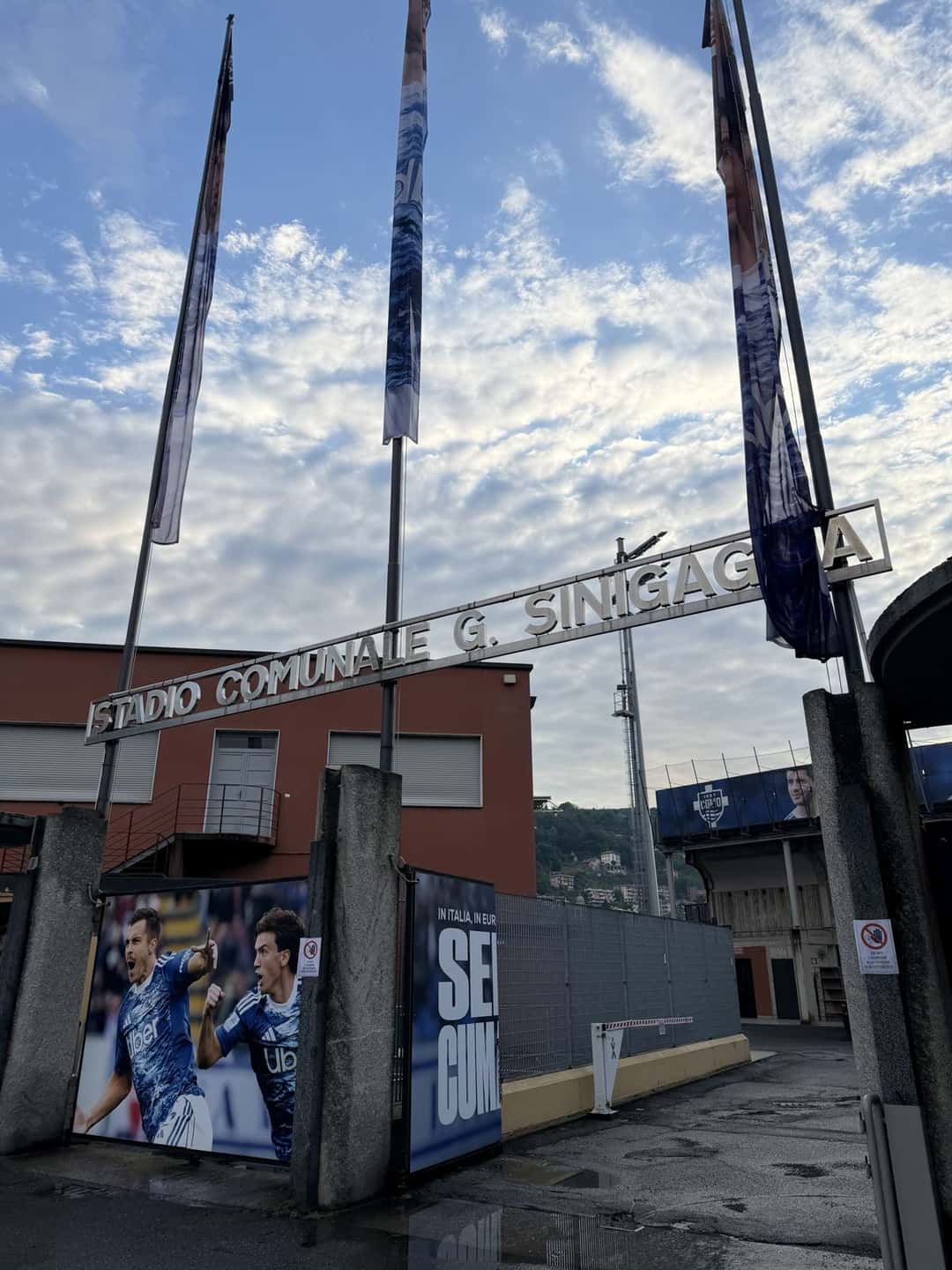 La entrada del estadio Giuseppe Sinigaglia, en Como, con el cartel de hierro con su nombre y las banderas del club; foto de archivo de mayo de 2026 (foto: Byxelized, Wikimedia Commons, licencia CC BY-SA 4.0)