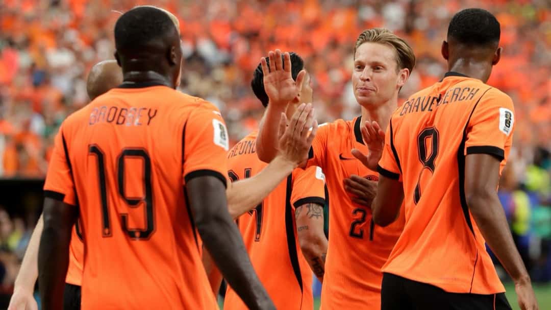 Frenkie de Jong y sus compañeros de Países Bajos, con la camiseta naranja, chocan las manos para festejar un gol con la tribuna llena de hinchas de naranja