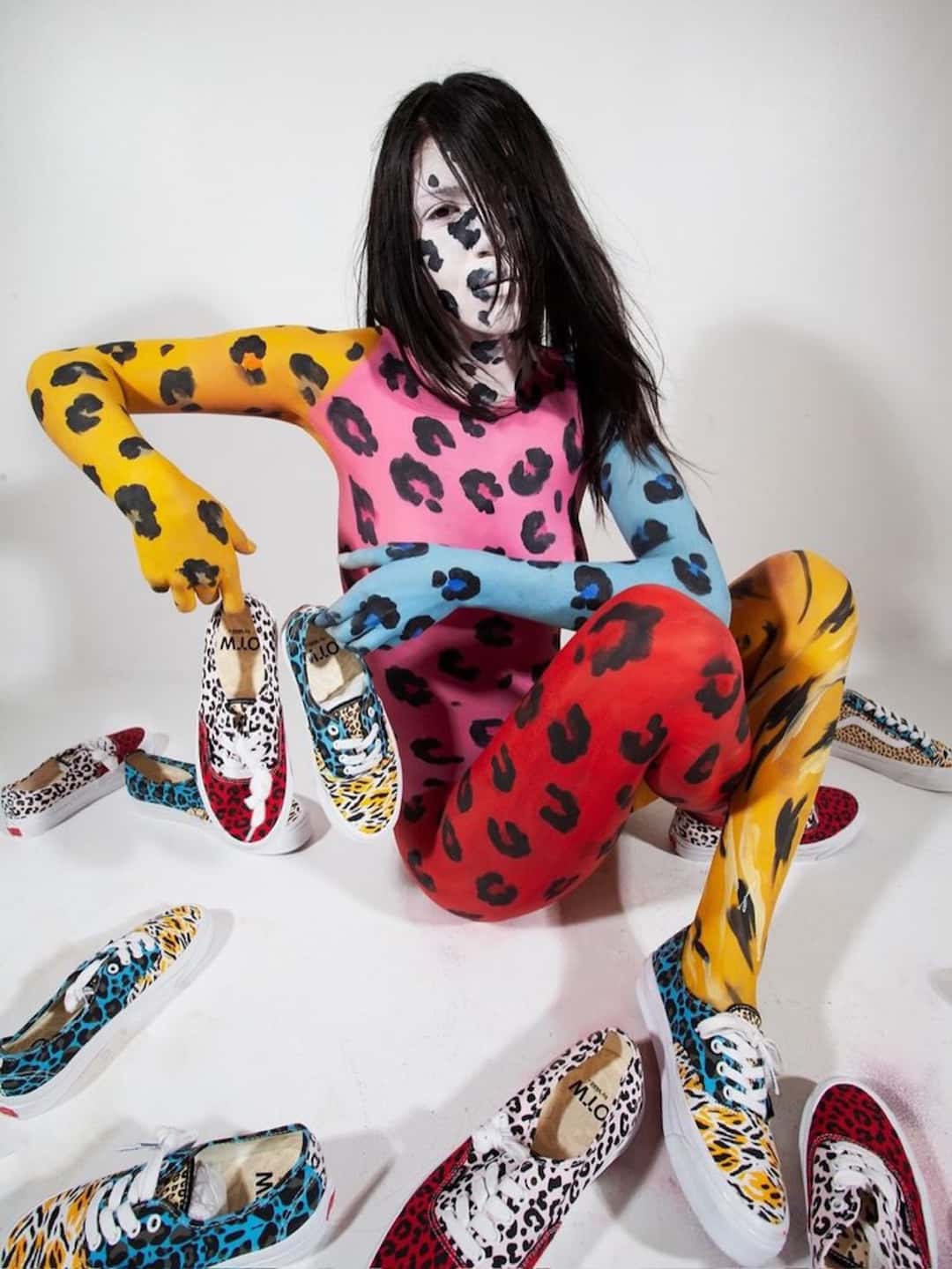 Campaña de Imran Potato x Vans con una modelo con el cuerpo pintado de manchas de leopardo en amarillo, rosa, celeste y rojo, rodeada de pares de Authentic desparejados