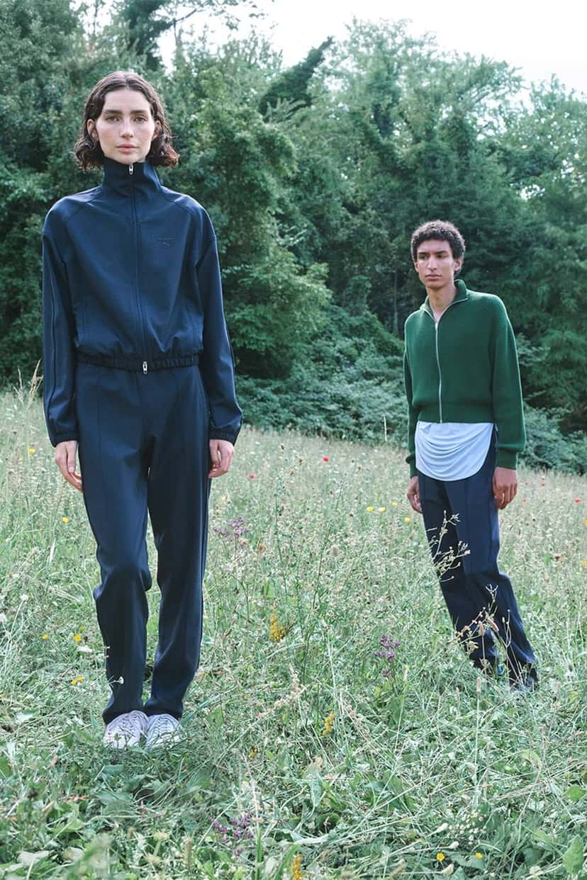 Dos modelos con el conjunto T7 de Jil Sander x PUMA en un campo con árboles de fondo