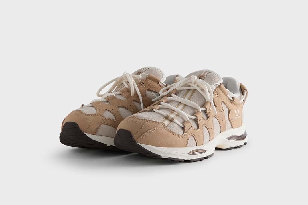 Par de la ASICS GEL-MAI 0.1 Safari de Giorgio Armani x Kith en diagonal sobre fondo gris claro, con capas de nubuck color camel sobre gamuza clara, cordones gruesos color crudo, águila de Giorgio Armani en el lateral y mediasuela blanca con detalles marrón oscuro