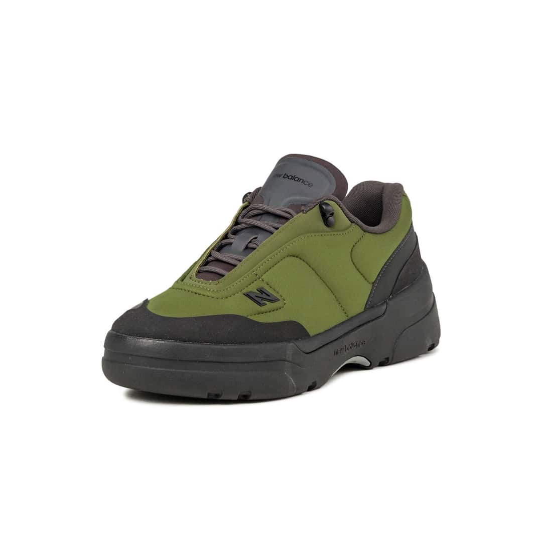 New Balance TL900 Sport Green/Black en vista de tres cuartos, con el upper verde oliva acolchado en paneles, cordones grises con traba y la lengüeta gris oscura con la marca New Balance