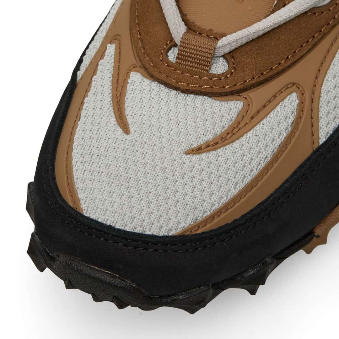 Detalle de la punta de la Reebok Spike Racer, con la malla gris clara, las piezas de cuero marrón en forma de llama y el borde negro de la suela
