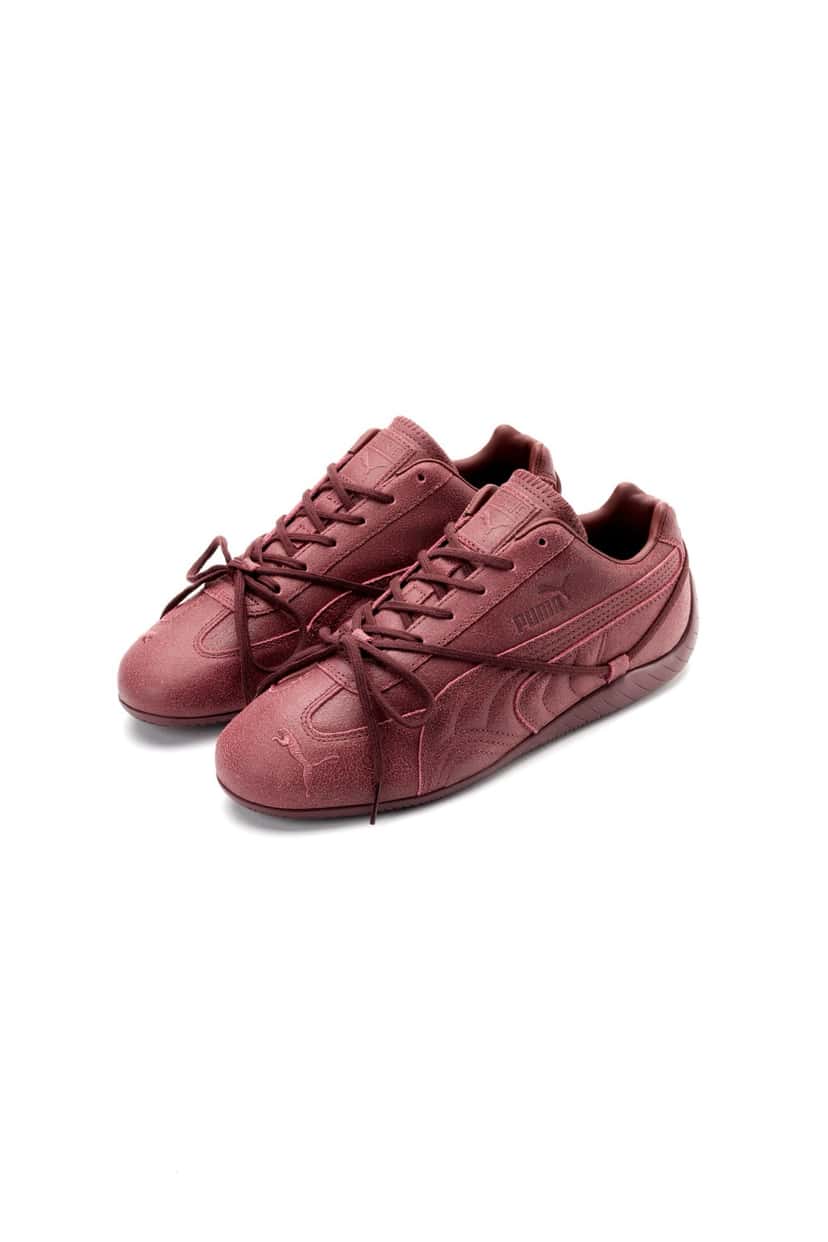 Par de PUMA x ROSÉ Speedcat VTG Burgundy sobre fondo blanco, en nobuck bordó con textura gastada, Formstrip y logo PUMA tono sobre tono y cordones largos que cruzan por encima del upper