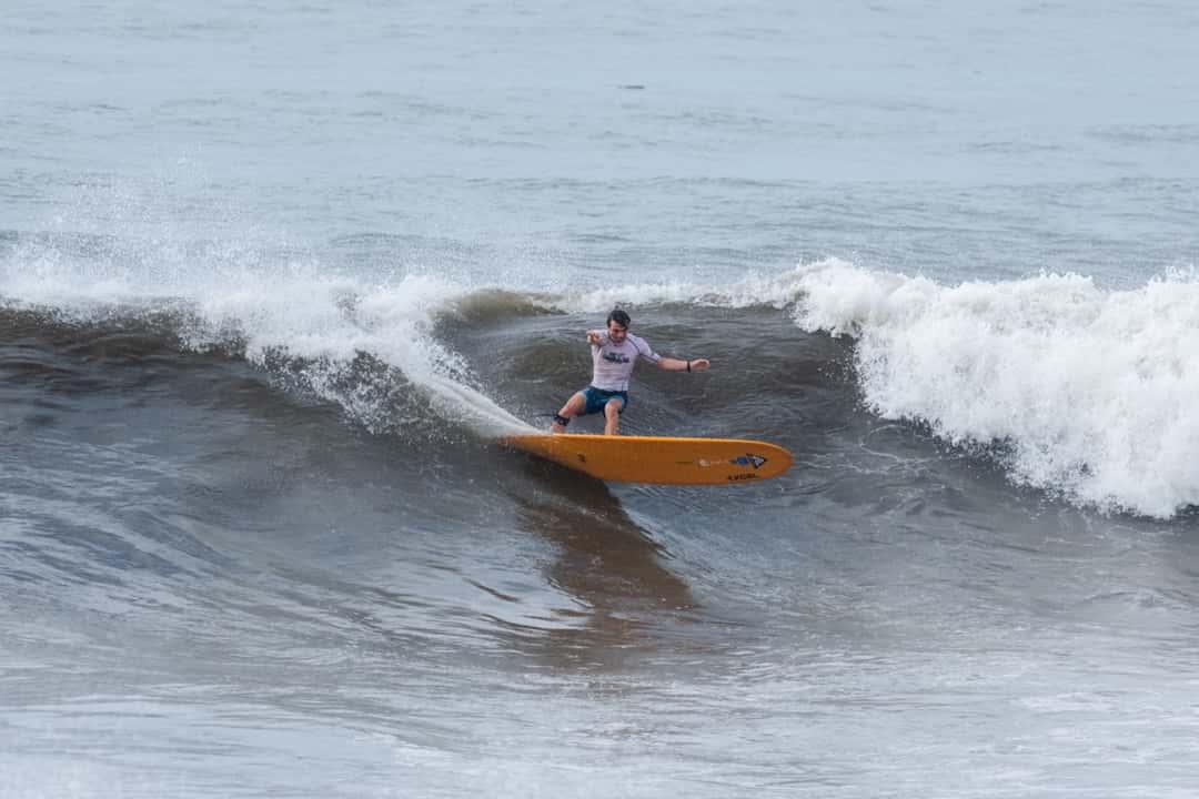 Douwe Robroch, con lycra blanca, gira sobre un longboard naranja en una ola de El Sunzal