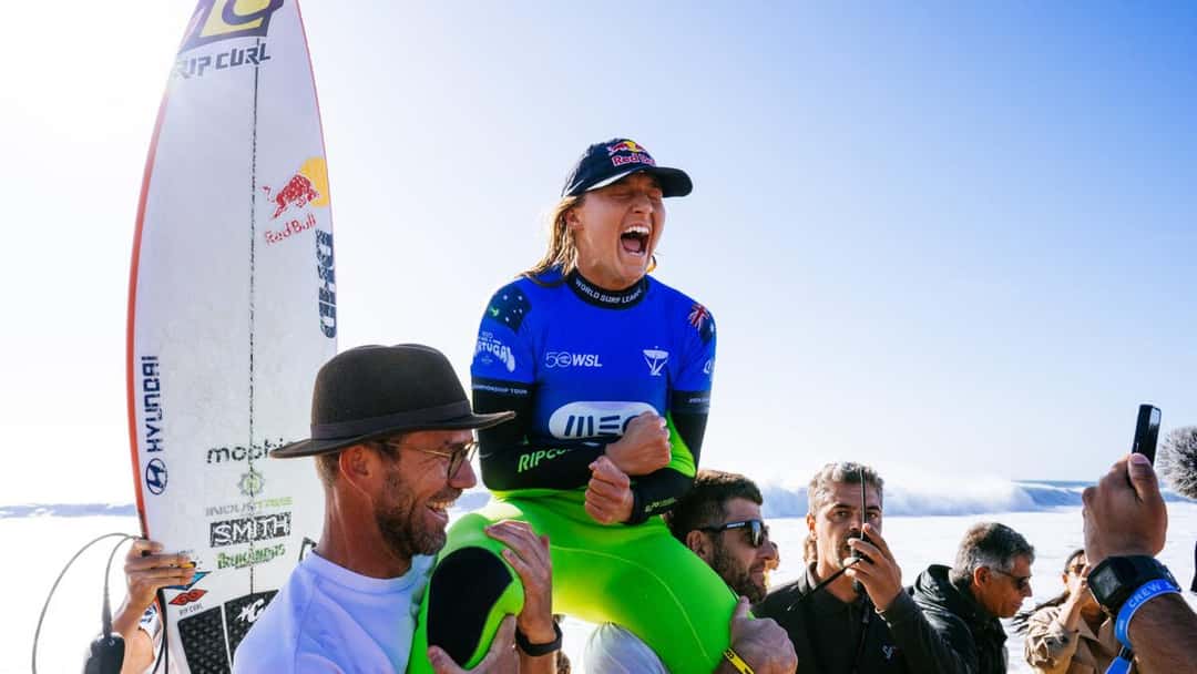 Molly Picklum, con la lycra azul de la WSL y el traje verde, grita de emoción mientras la llevan en andas por la arena de Supertubos (foto de archivo)