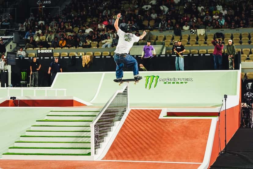 Giovanni Vianna, de remera blanca y jean, sube con la tabla en boardslide por la baranda de la escalera, frente a la tribuna de Roland-Garros