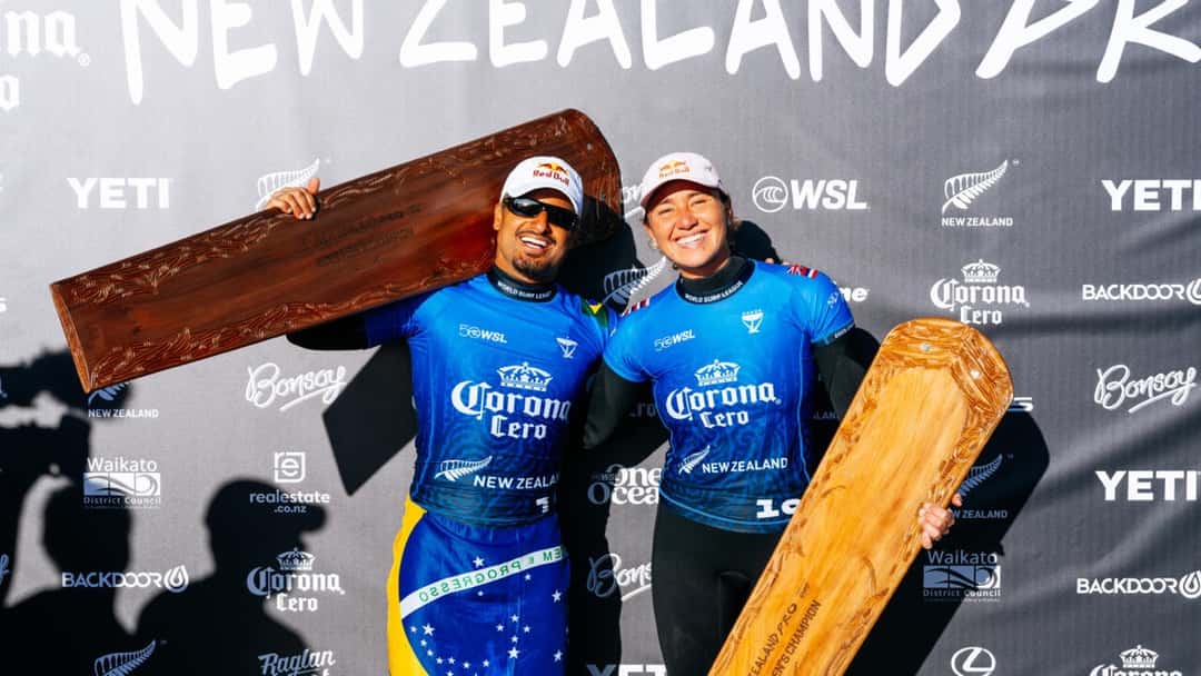 Carissa Moore e Ítalo Ferreira sostienen los trofeos de campeones del New Zealand Pro, con forma de tabla de madera tallada, en mayo de 2026 (foto de archivo)