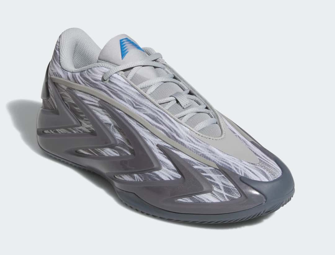 adidas Anthony Edwards 3 Snow Camo en vista de tres cuartos, con el camuflaje gris y blanco, los cordones grises y el logo AE azul en la lengüeta