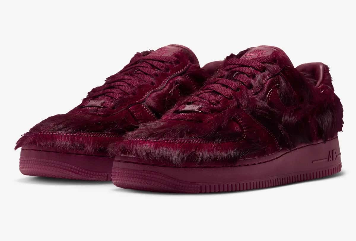 Par del Nike Air Force 1 Low Pony Hair Team Red en vista de tres cuartos sobre fondo gris claro, con pelo largo bordó en todo el upper, cordones, mediasuela y suela del mismo tono