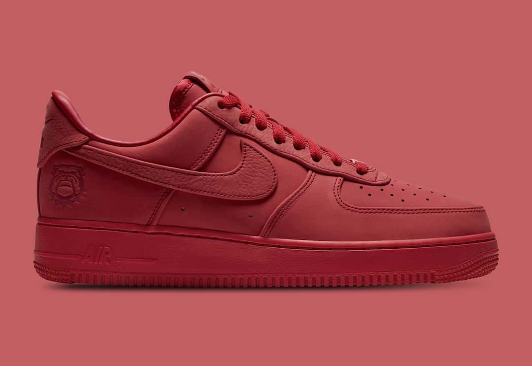 Nike Air Force 1 Low Luxe de la Universidad de Georgia de perfil lateral sobre fondo rojo, entero en rojo de la capellada a la suela, con cordones rojos y la cara de un bulldog grabada en el talón