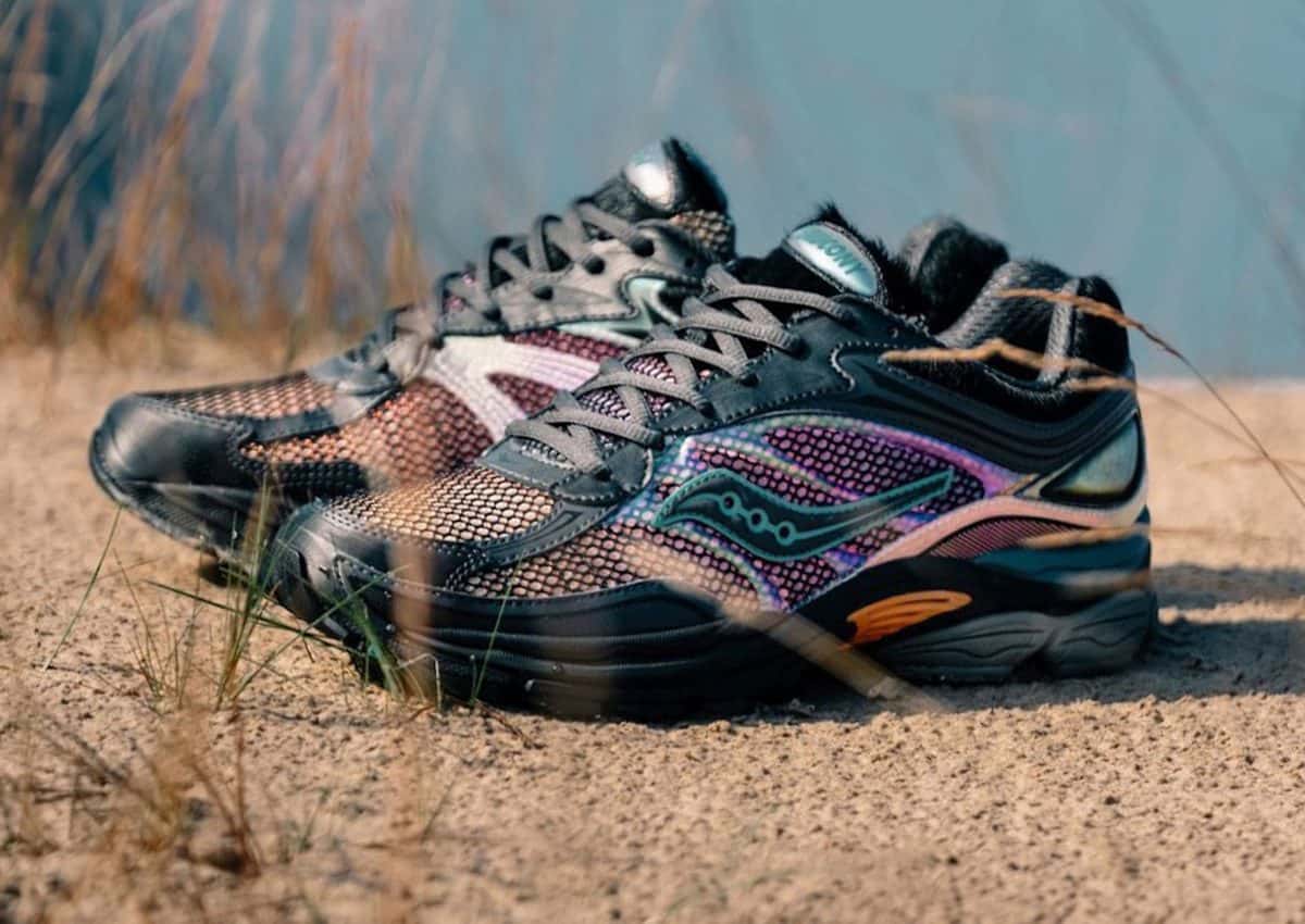 Par de afew x Saucony ProGrid Omni 9 Tara Hawk sobre arena, con paneles plateados y negros, malla violeta y rosada y detalles naranjas en la suela