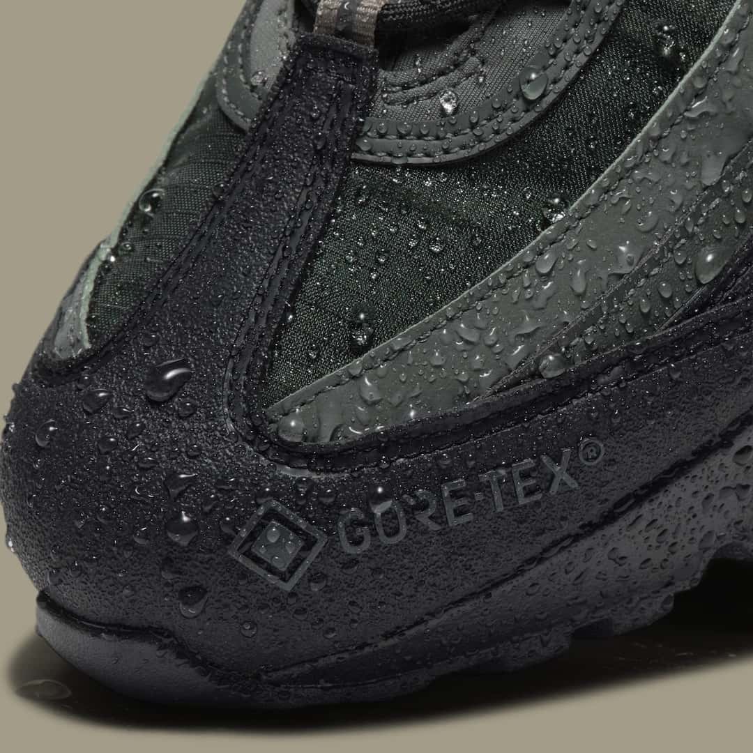 Primer plano de la puntera del Nike Air Max 95 Gore-Tex Camo Green con gotas de agua sobre el cuero negro y el logo Gore-Tex