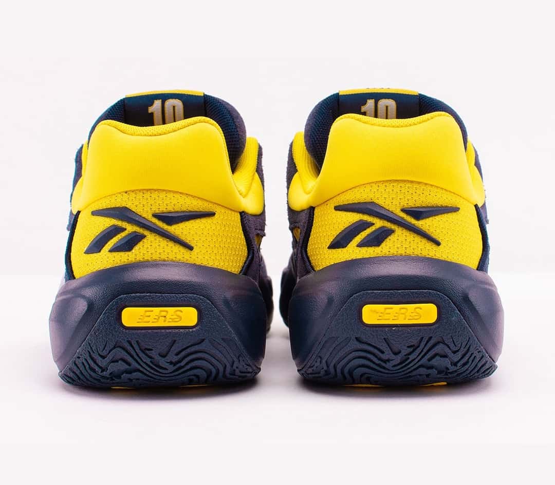 Talones de la Reebok Engine A 26 Brew Crew en amarillo, con el logo de Reebok en azul marino y la suela azul