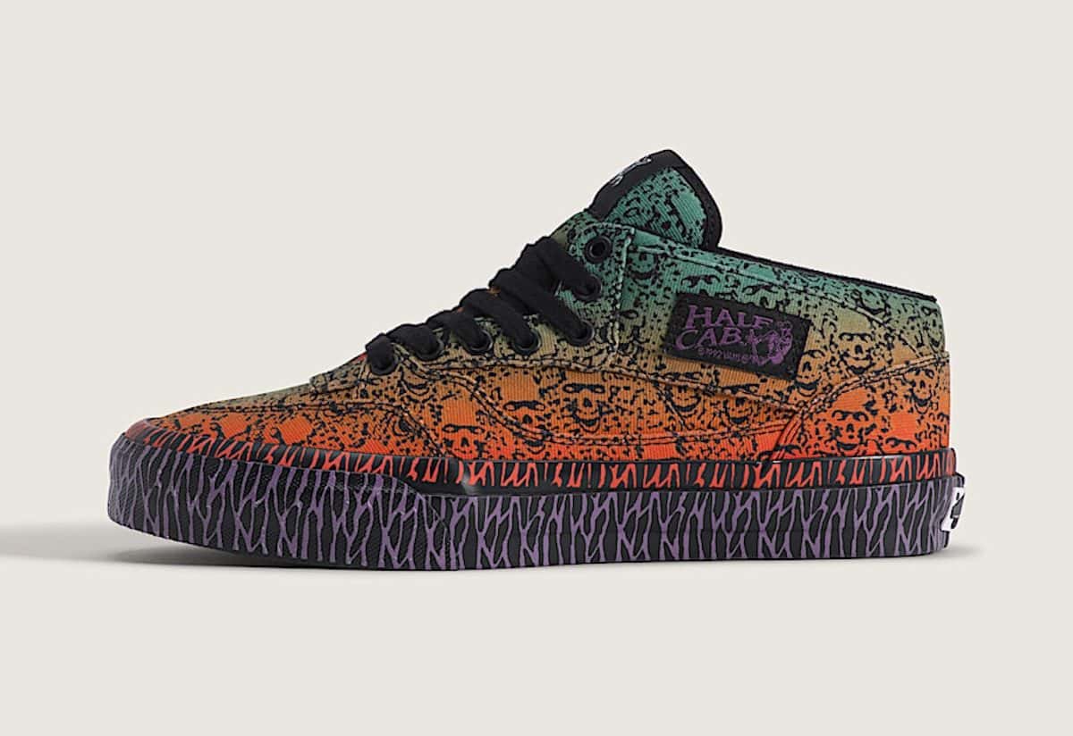 Bad Idea by Chito x Vans Half Cab 33 de perfil sobre fondo gris claro, con calaveras negras sobre un degradé de verde a naranja y la entresuela negra con rayas violetas