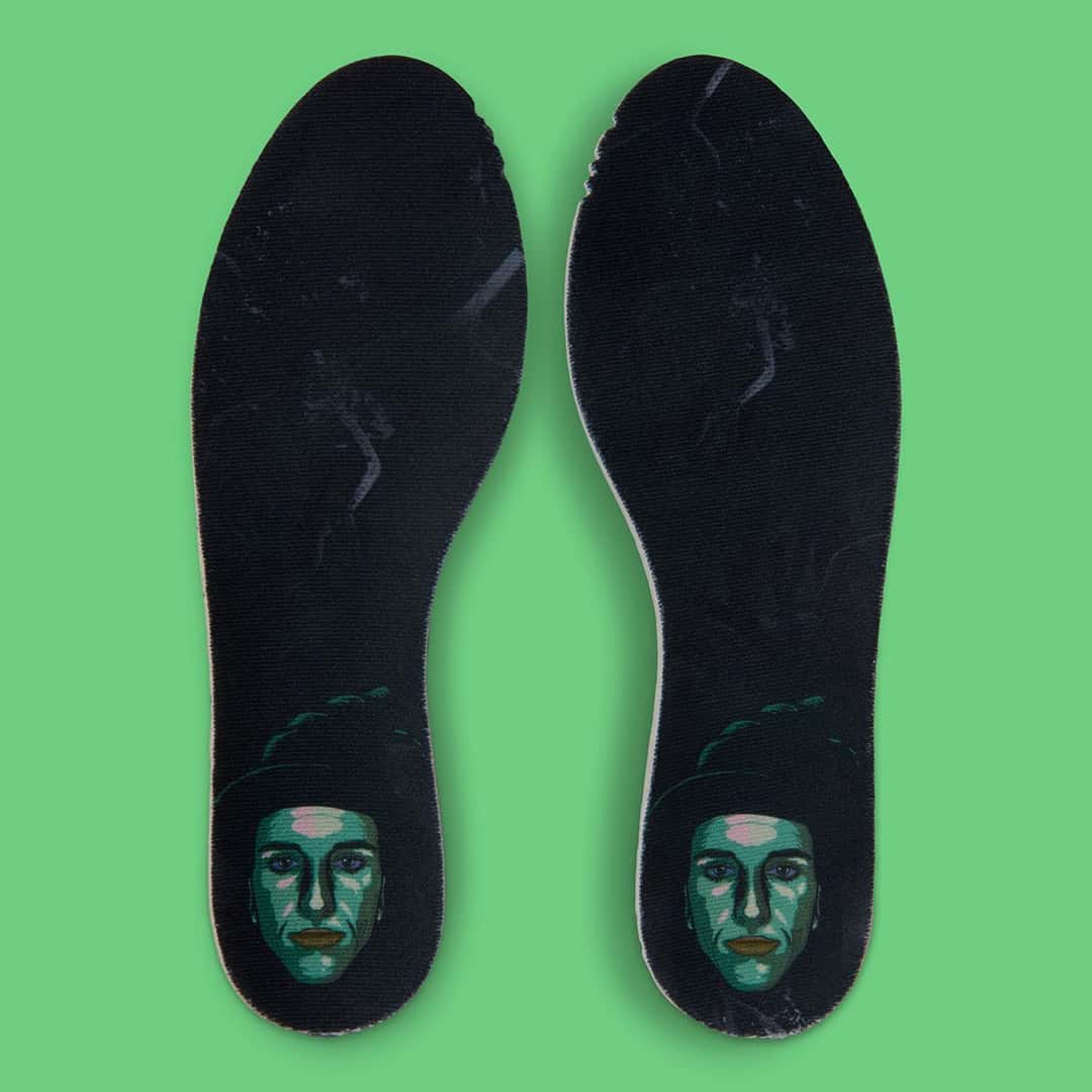 Plantillas negras de la Nike Caitlin 1 Jinx con un retrato de cara verde a la altura del talón