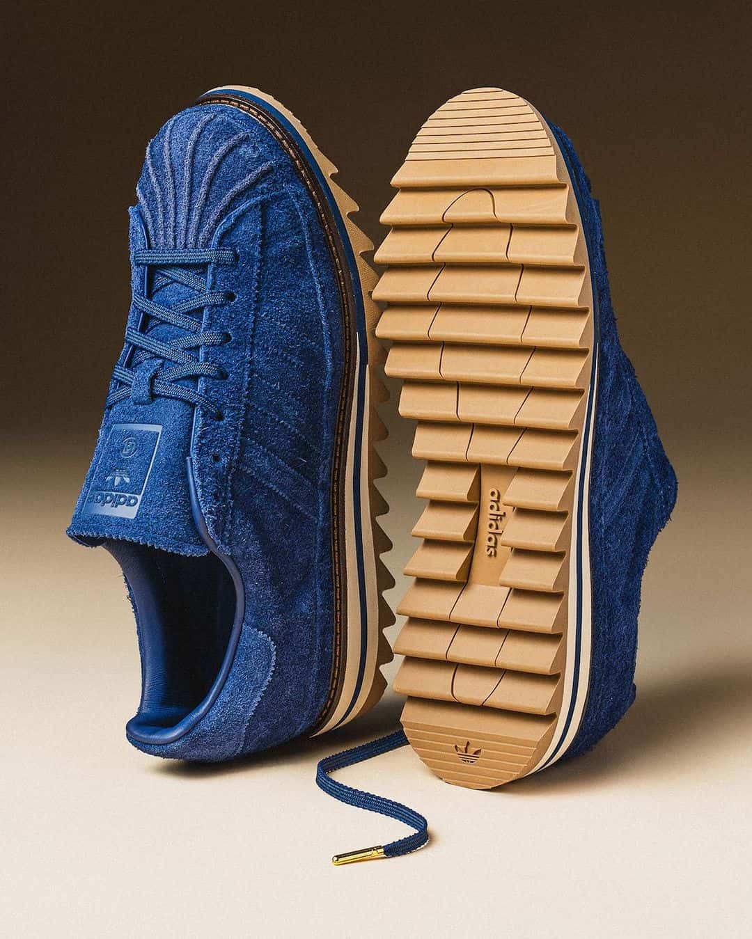 Suela dentada color goma de la adidas Superstar de CLOT junto al par azul de gamuza