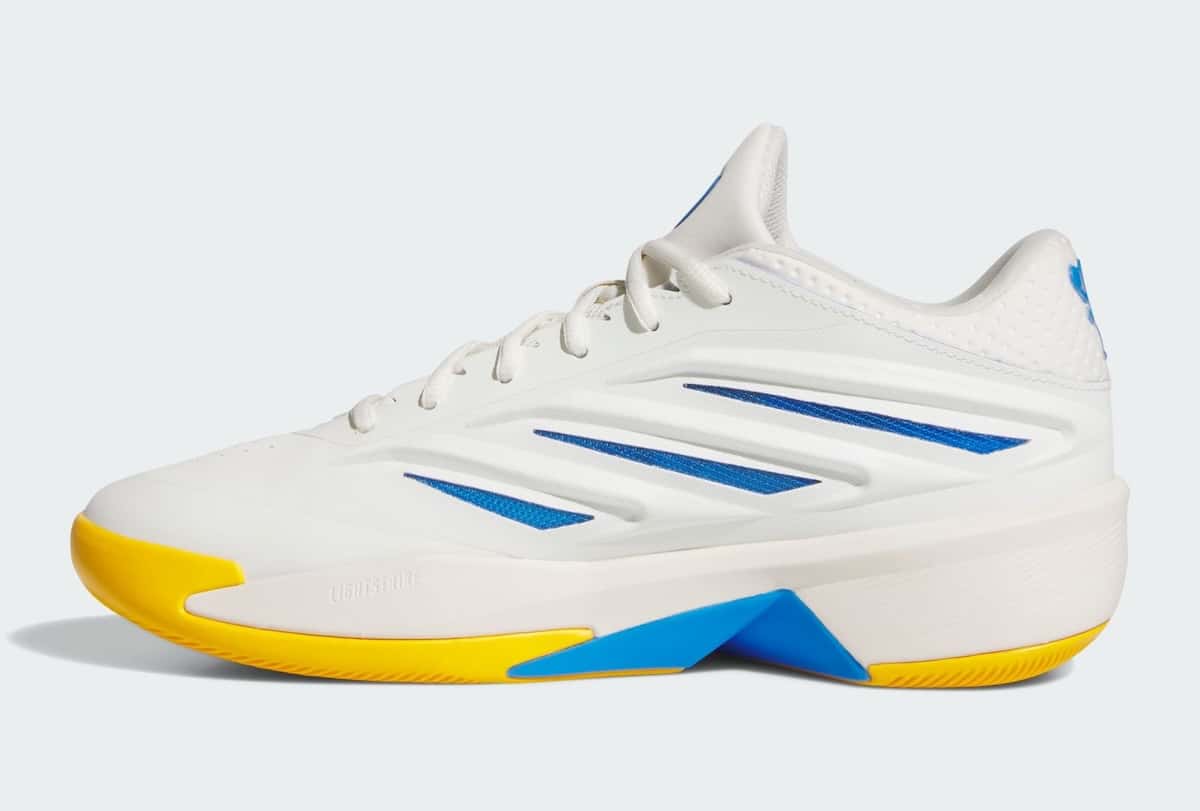 Perfil lateral de la adidas Crazy Energy Wagner Brothers sobre fondo gris claro, con upper blanco hueso, tres tiras azules, suela amarilla y un detalle azul en la mediasuela con la palabra Lightstrike