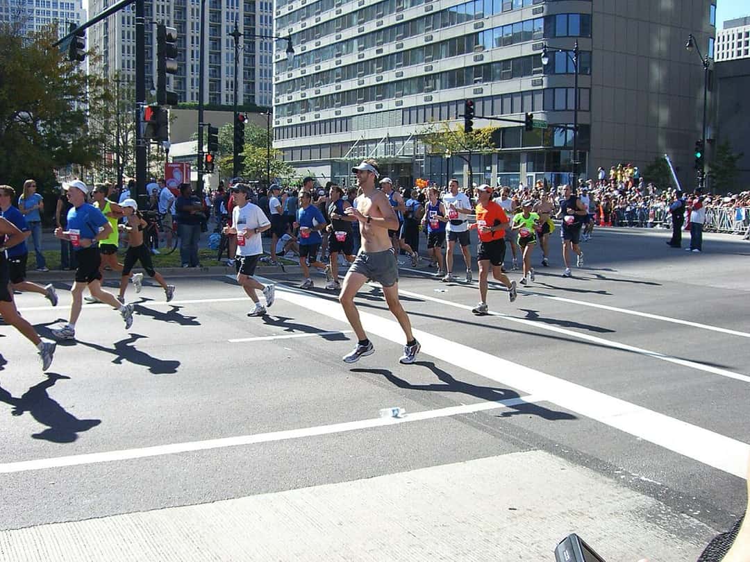 Corredores con remeras de colores avanzan por una avenida del centro de Chicago, entre edificios y público detrás de las vallas, durante el maratón de 2008