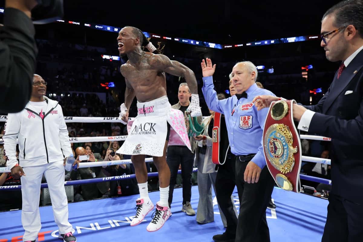 O'Shaquie Foster grita y festeja sobre el ring de San Antonio, mientras le acercan los cinturones de campeón del superpluma