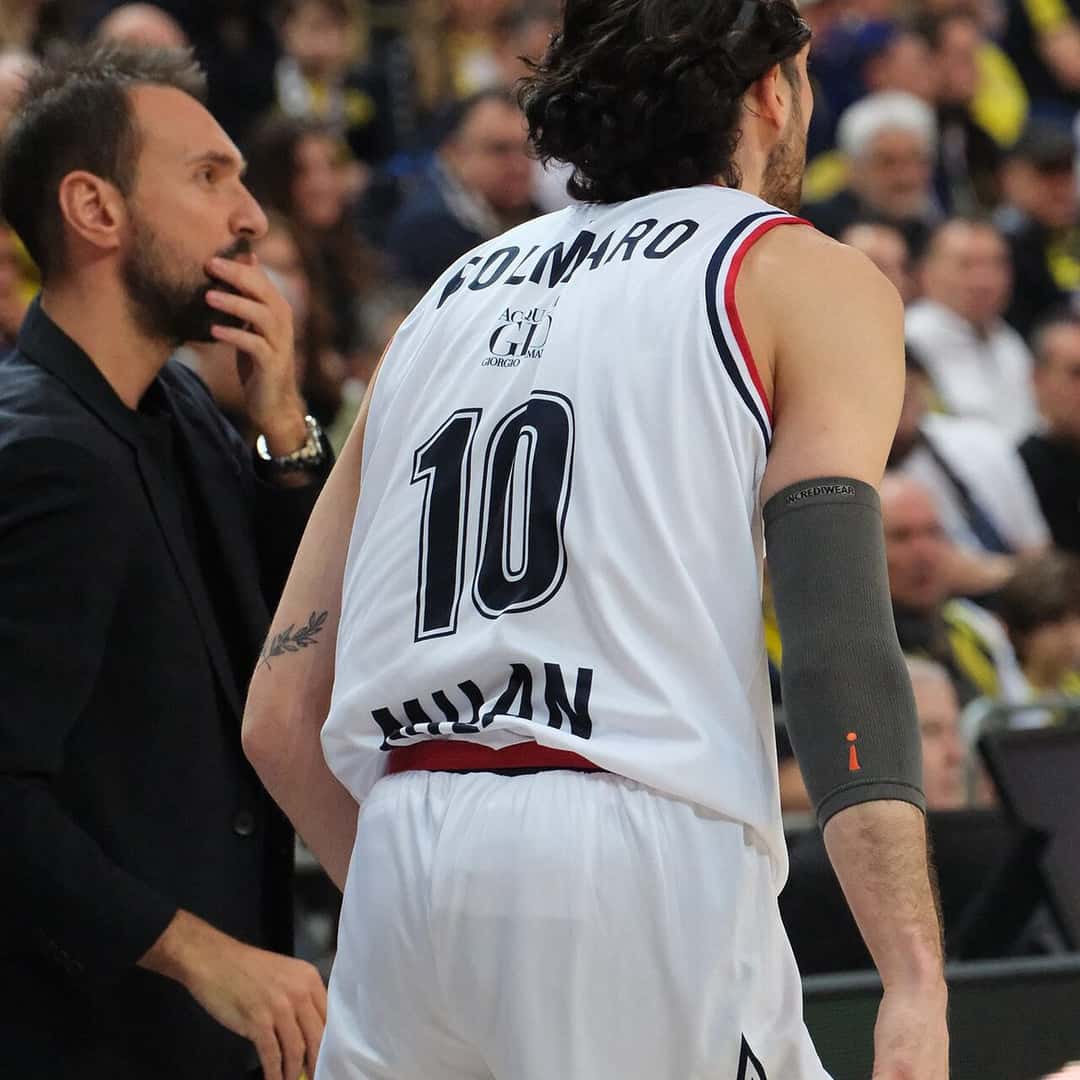 Foto de archivo: Leandro Bolmaro, de espaldas con la camiseta blanca número 10 del Olimpia Milano, junto a un hombre de traje durante un partido de Euroliga