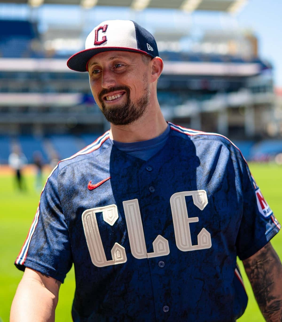 Foto de archivo: Shawn Armstrong, lanzador de los Cleveland Guardians, sonriendo en el campo de Progressive Field, con gorra blanca y azul con la C roja y camiseta azul con las letras CLE