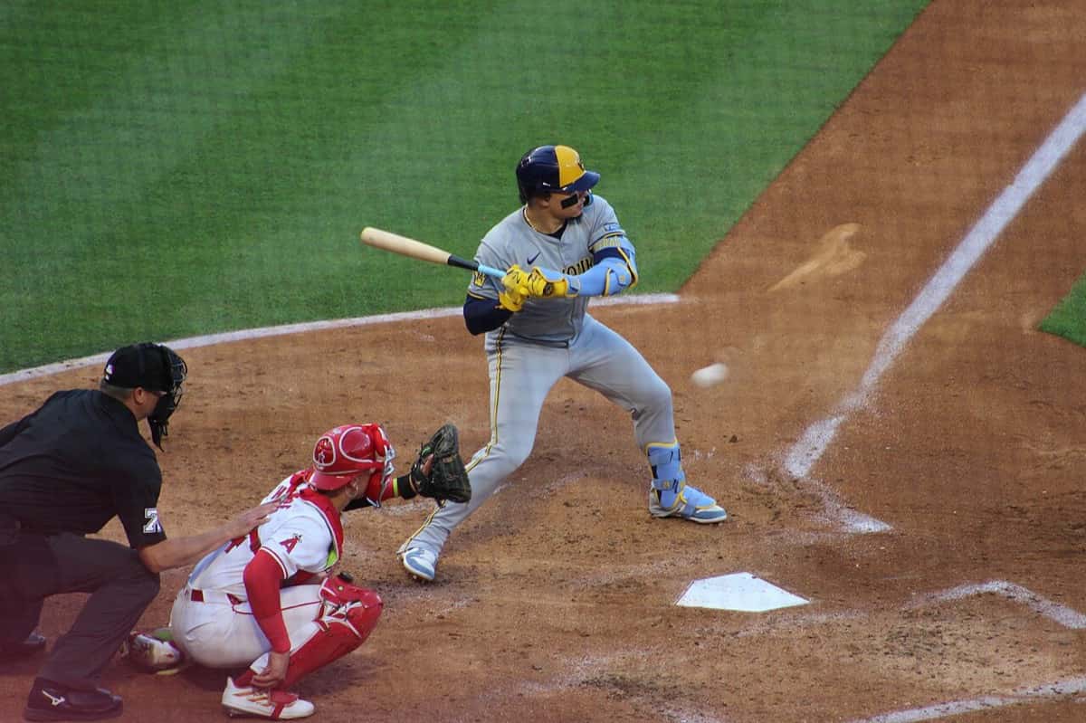 Foto de archivo: William Contreras, de los Milwaukee Brewers, con uniforme gris de visitante y casco azul y amarillo, esperando un lanzamiento en el cajón de bateo, con el catcher y el umpire detrás