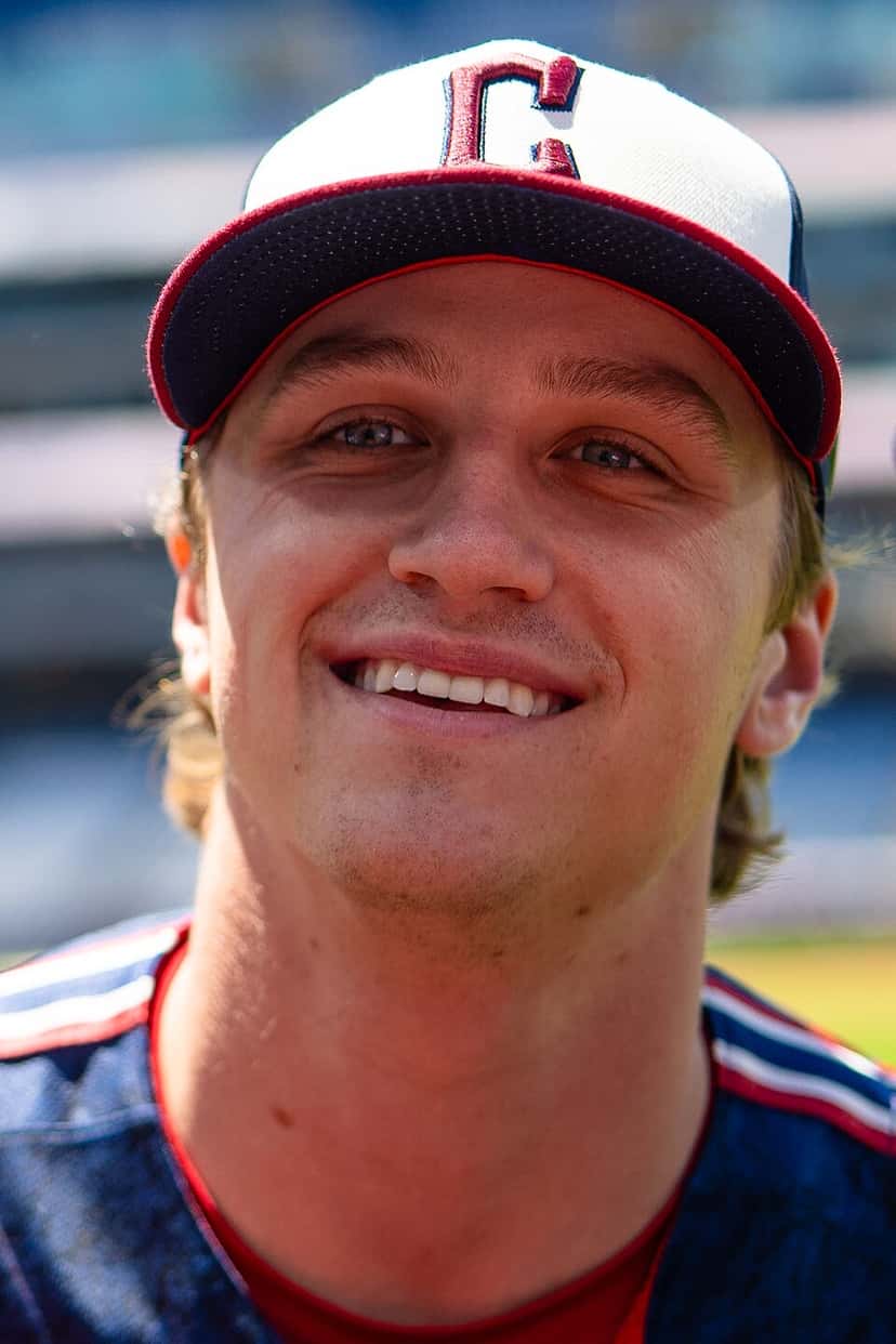 Foto de archivo: Petey Halpin, de los Cleveland Guardians, sonriendo, con gorra blanca y azul con la C roja y camiseta azul con vivos rojos, en un estadio desenfocado detrás