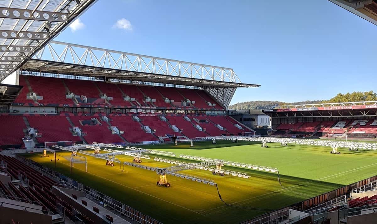 Foto de archivo: el estadio Ashton Gate de Bristol vacío, con las tribunas rojas y la cancha iluminada por lámparas de crecimiento, en un día de sol