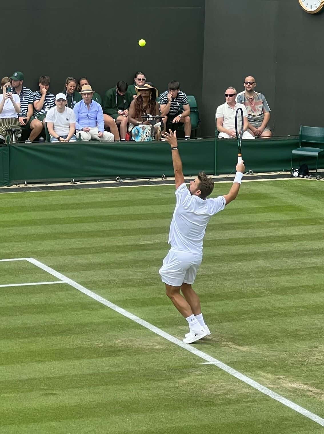 Foto de archivo: Stan Wawrinka, de blanco, lanza la pelota hacia arriba para sacar en una cancha de césped de Wimbledon, en 2023