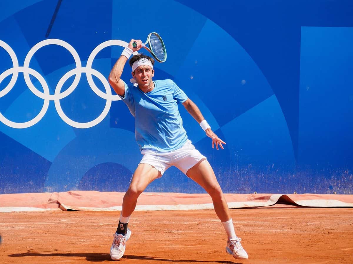 Foto de archivo: Tomás Martín Etcheverry, con remera celeste, le pega un drive en una cancha de polvo de ladrillo en los Juegos Olímpicos de París 2024