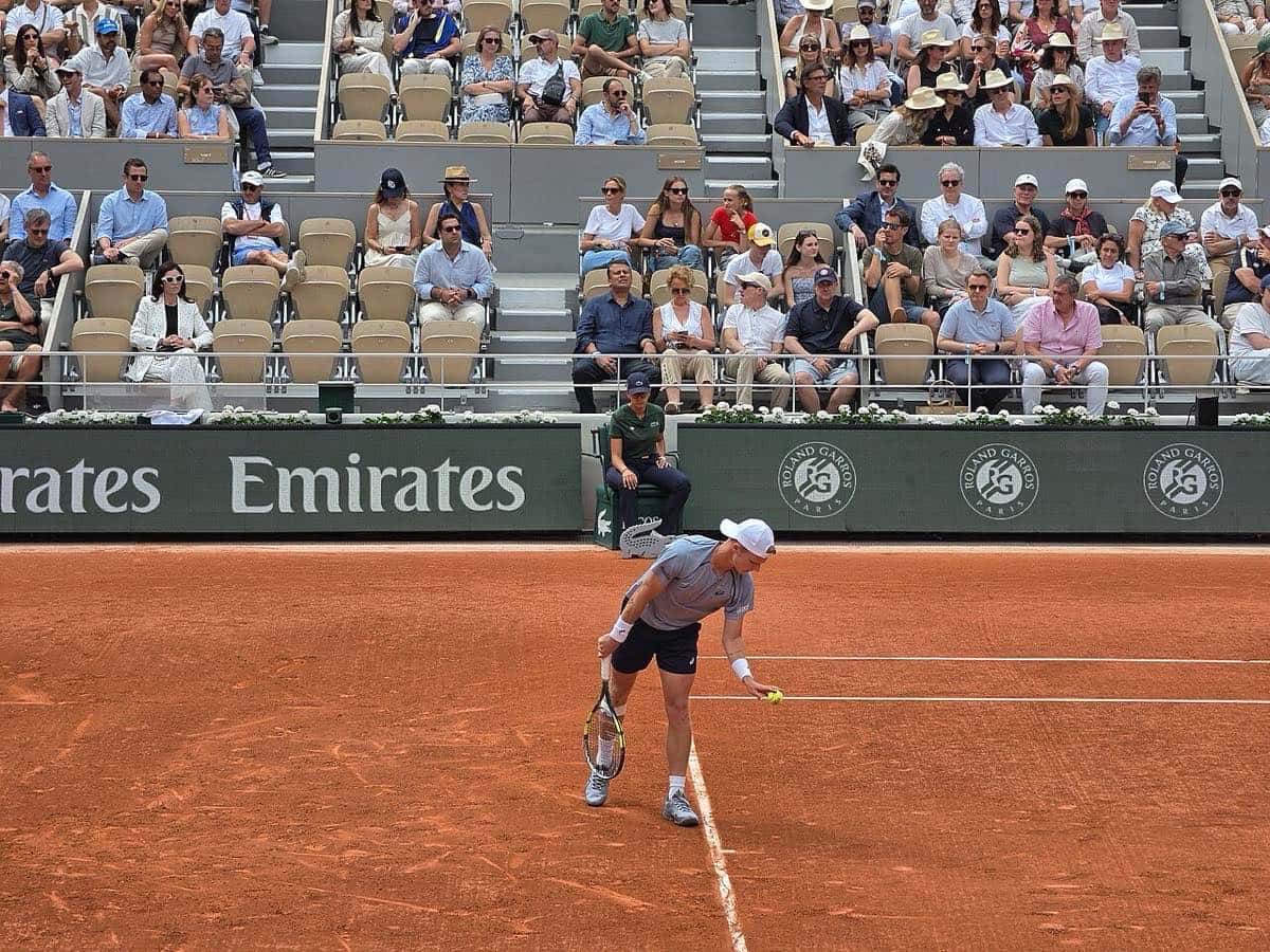 Foto de archivo: Alexander Zverev, con gorra blanca, remera celeste y short azul, saca en una cancha de polvo de ladrillo de Roland Garros 2026