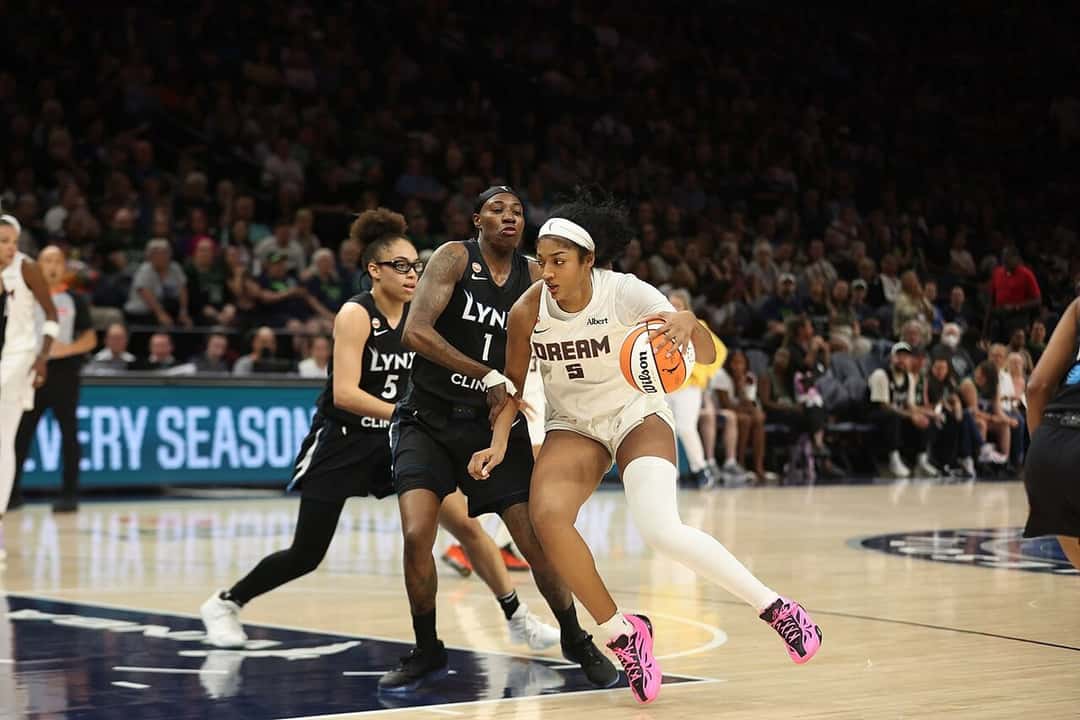 Foto de archivo: Angel Reese, con la camiseta blanca número 5 de Atlanta Dream, avanza con la pelota mientras la marcan dos jugadoras de Minnesota Lynx, de negro