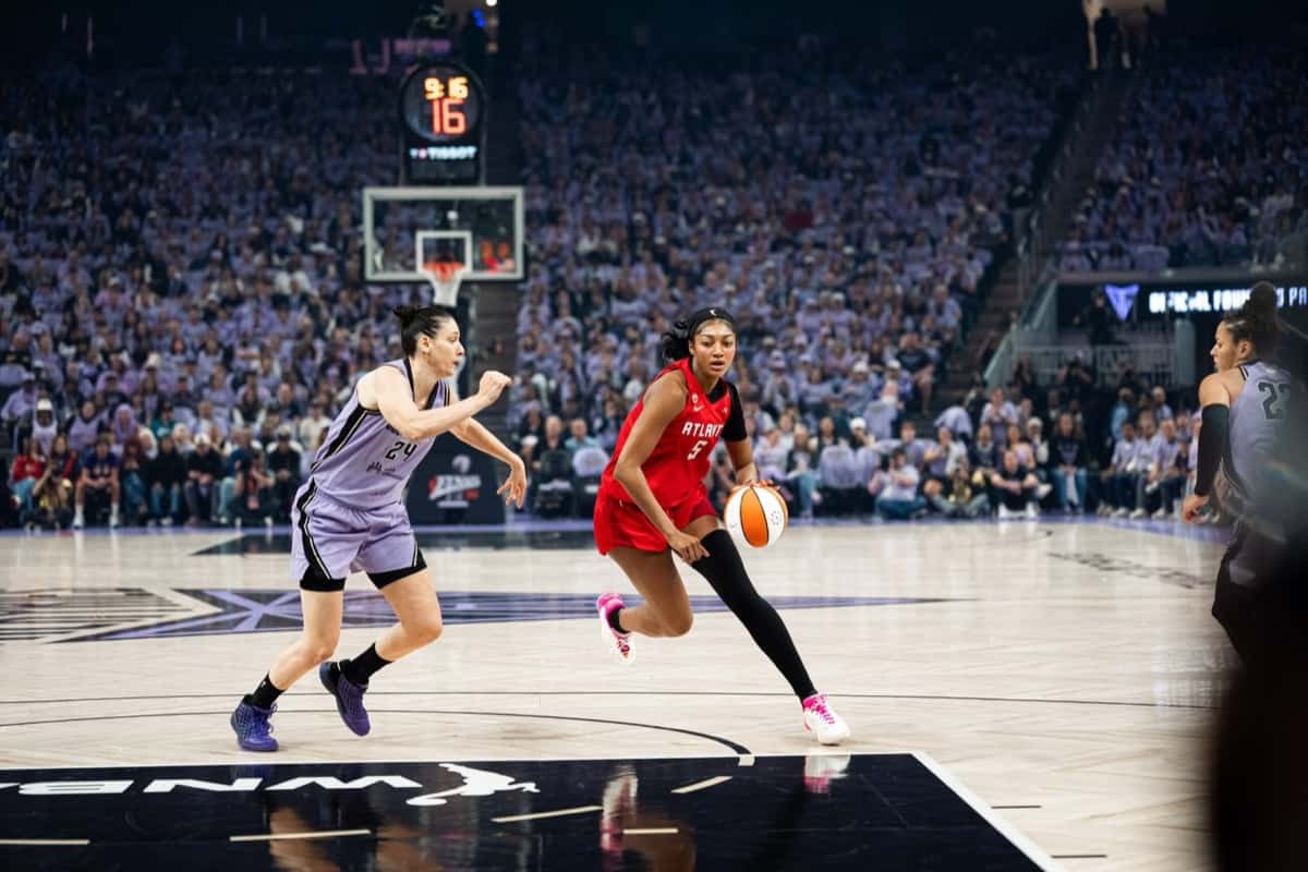 Angel Reese, con la camiseta roja del Atlanta Dream, avanza con la pelota marcada por una jugadora de las Valkyries, de violeta, en el Chase Center