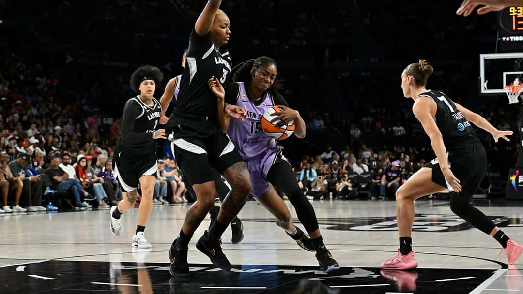 Una jugadora de Golden State Valkyries con la camiseta 15 avanza con la pelota entre jugadoras de Las Vegas Aces vestidas de negro