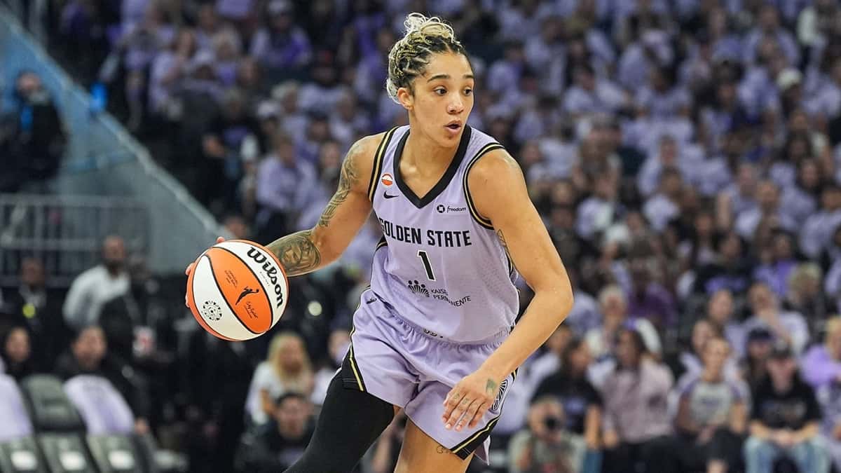 Gabby Williams, con la camiseta 1 lila de Golden State Valkyries, avanza con la pelota frente a una tribuna llena de hinchas vestidos de violeta en el Chase Center