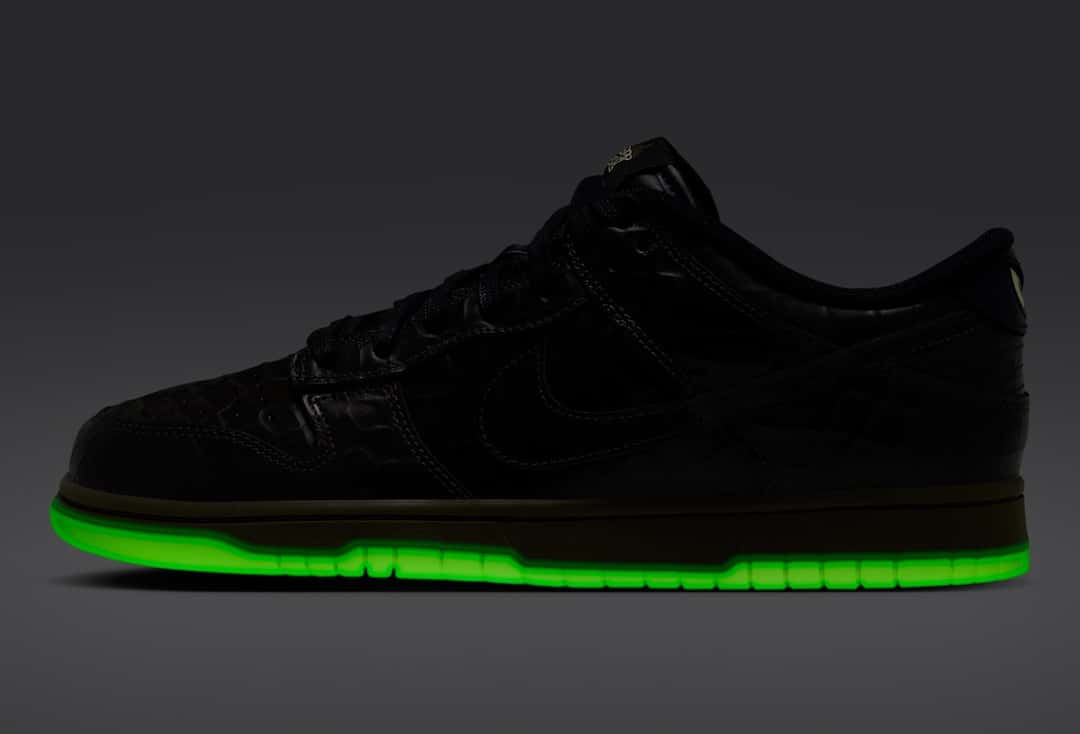 Nike Dunk Low Shibuya Halloween de perfil en la oscuridad, con la suela encendida en verde fluorescente y el upper negro casi invisible