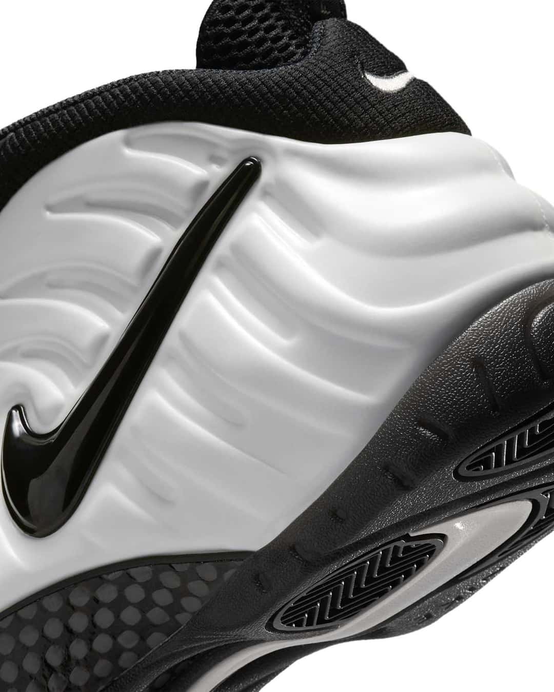 Primer plano del lateral de la Nike Air Foamposite Pro Premium Summit White con el Swoosh negro brillante sobre la carcasa blanca y la placa de fibra de carbono en el mediopié