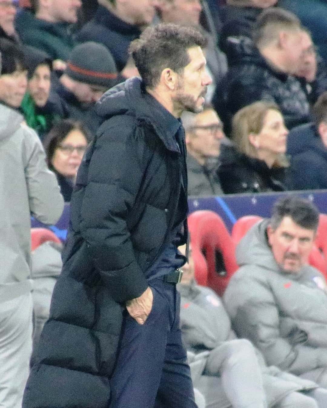 Diego Simeone, con una campera negra larga, sigue un partido de pie al costado de la cancha, delante del banco de suplentes; foto de archivo de enero de 2025 (foto: Werner100359, Wikimedia Commons, licencia CC BY-SA 4.0)