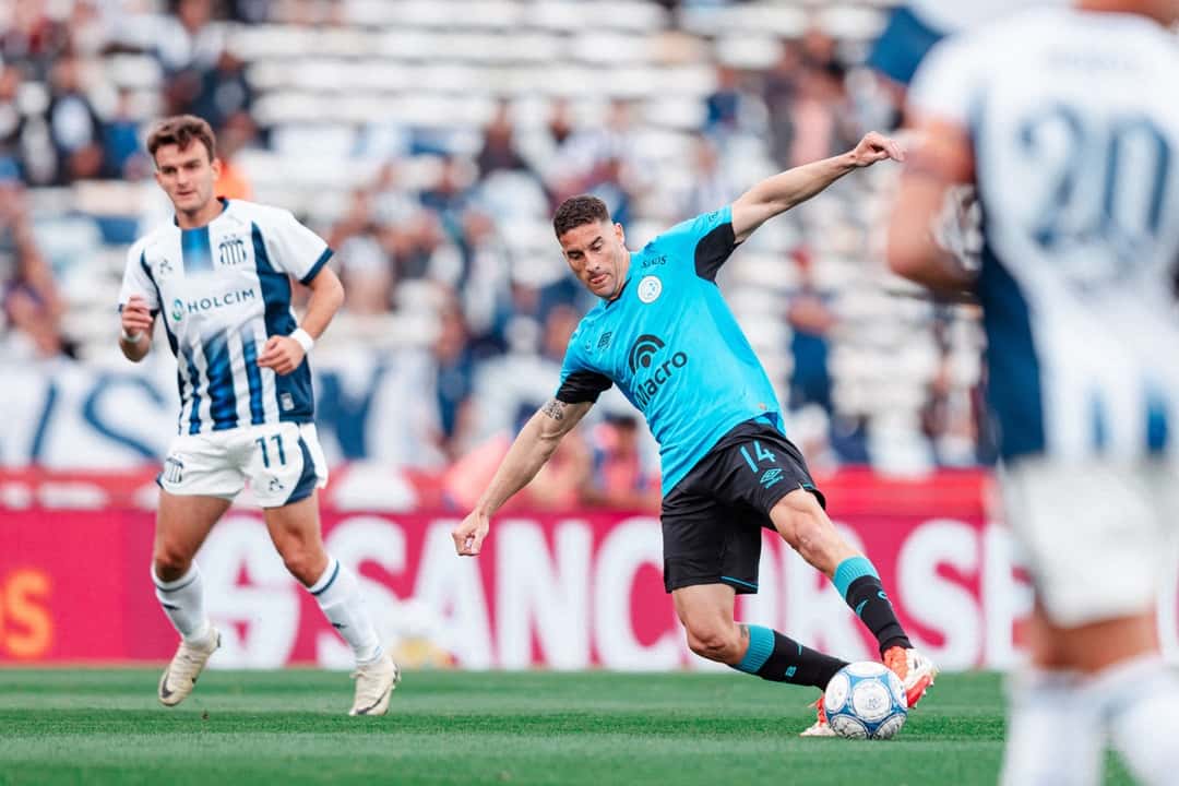 Un mediocampista de Belgrano le pega a la pelota ante la marca de un jugador de Talleres en el Kempes (foto: prensa Club Atlético Belgrano)