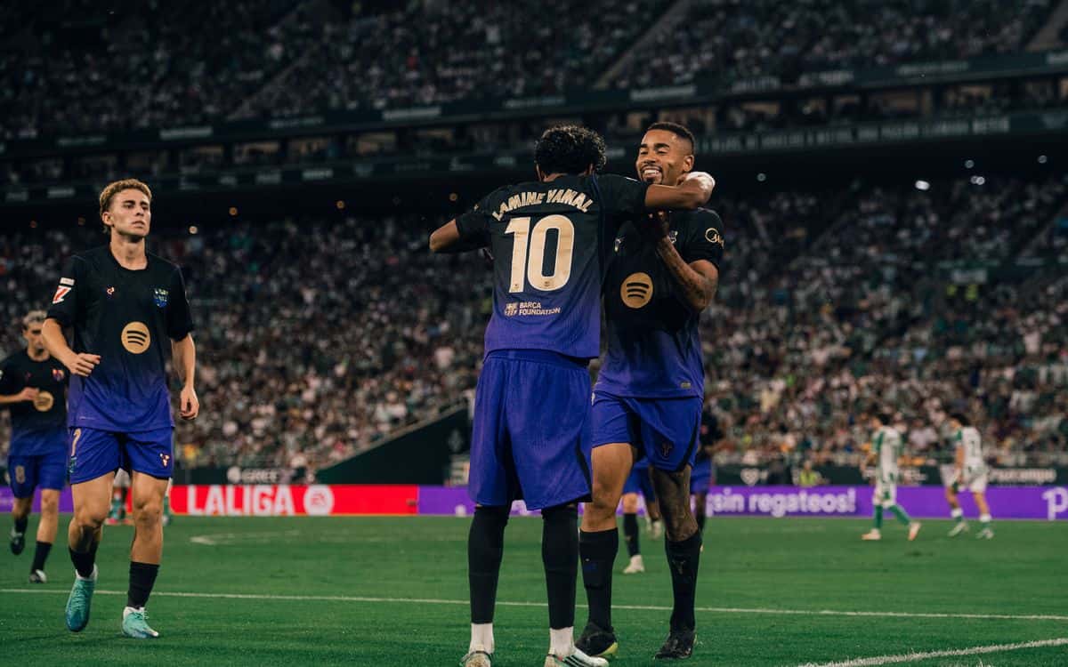 Lamine Yamal, de espaldas con el número 10 en la camiseta azul oscura del Barcelona, se abraza con un compañero para festejar un gol en La Cartuja ante el Betis (foto: prensa FC Barcelona)