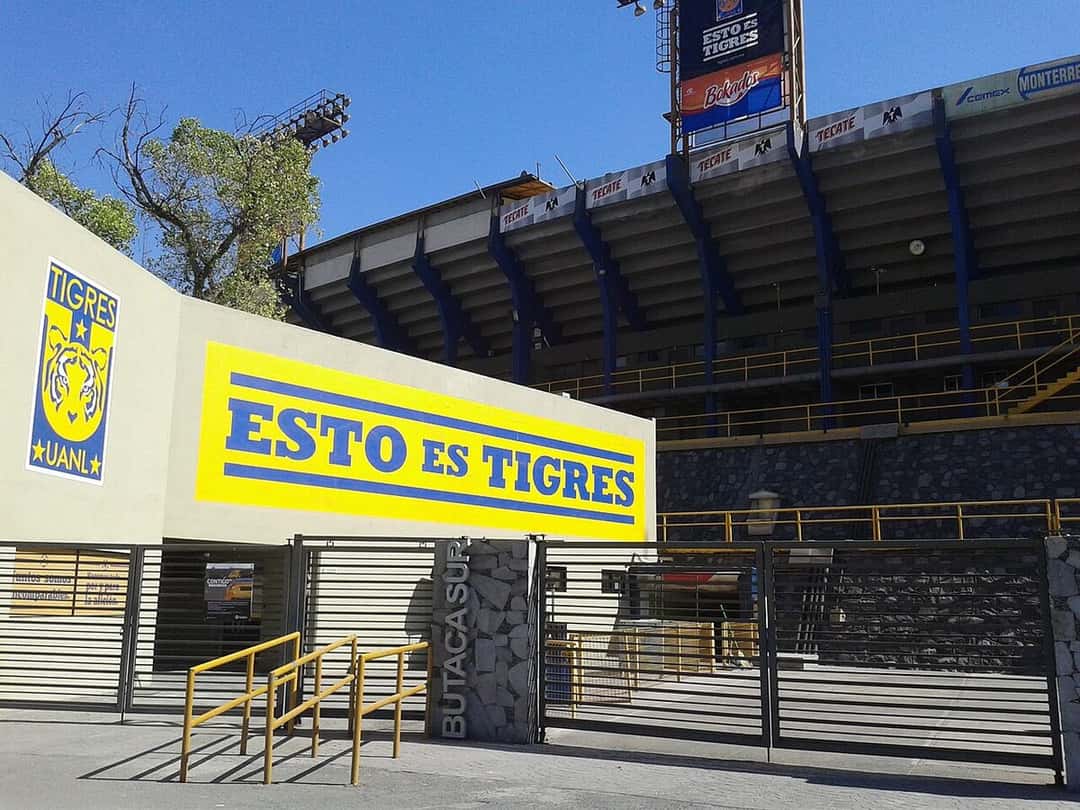 La entrada del estadio Universitario, con el escudo de Tigres y la frase «Esto es Tigres» en letras azules sobre fondo amarillo; foto de archivo de 2016 (foto: J4im31000, Wikimedia Commons, dominio público)
