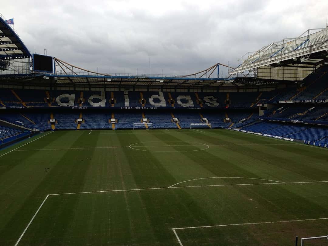 La cancha de Stamford Bridge vista desde la tribuna, con las butacas azules y el césped vacío; foto de archivo de febrero de 2013 (foto: WorldTraveller101, Wikimedia Commons, licencia CC BY-SA 3.0)