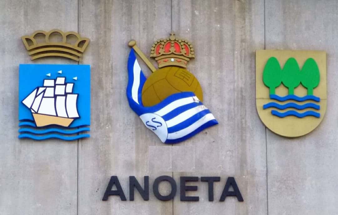 El escudo de la Real Sociedad entre los de San Sebastián y Guipúzcoa, sobre la palabra Anoeta, en la fachada del estadio del club; foto de archivo de 2022 (foto: Zarateman, Wikimedia Commons, dominio público CC0)